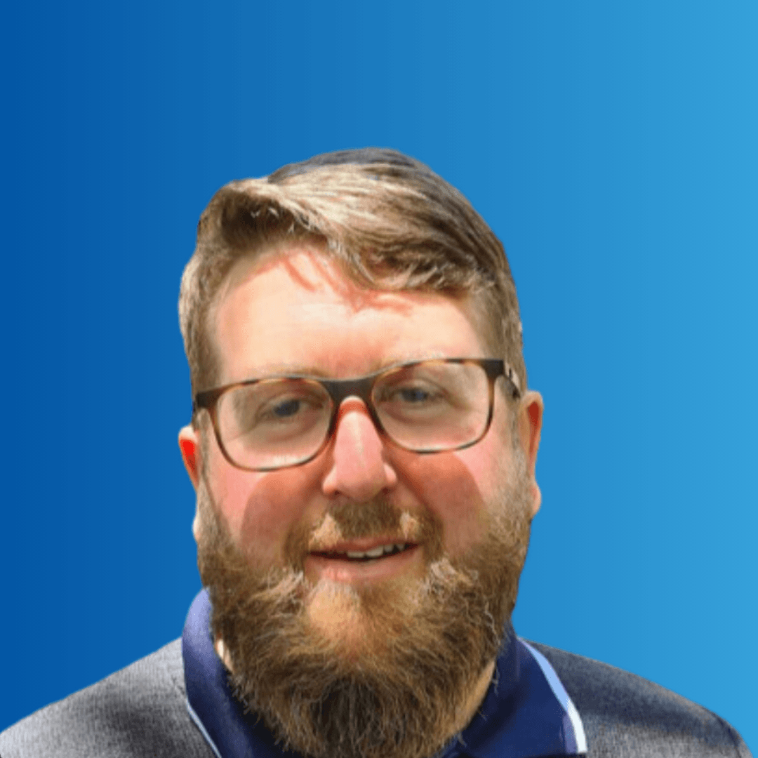 A man in glasses smiling at the camera on a blue background